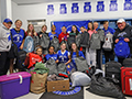  basketball team poses with backpacks and bins/suitcases of donated clothing and items.